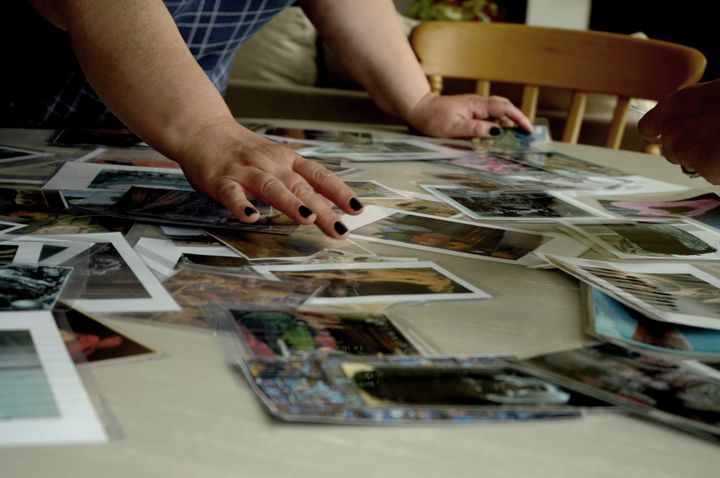 Mains qui étalent de nombreux tirages photo sur une table
