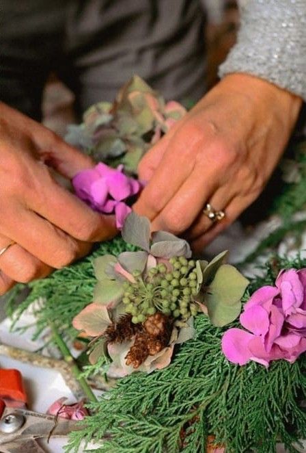 Mains composant une couronne d'hortensias et de branches de thuya pendant un atelier déco nature