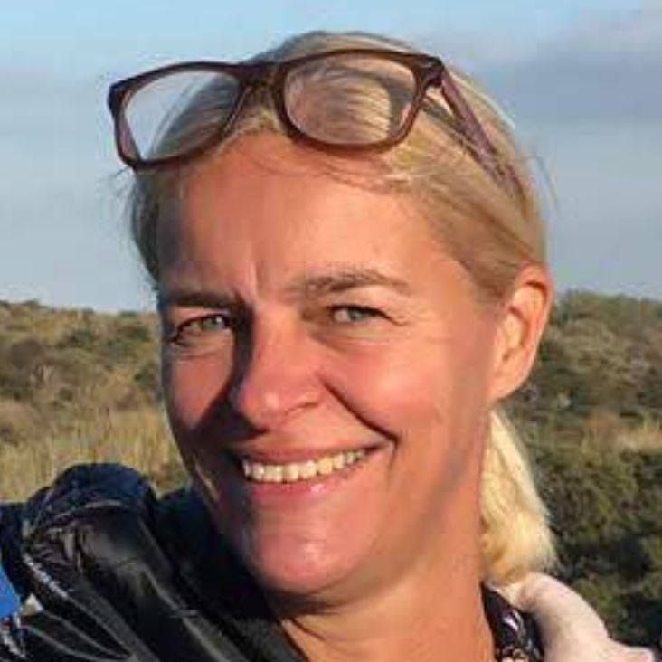 Christine den Boer, coach et psychopraticienne, souriante en extérieur, lunettes relevées sur la tête